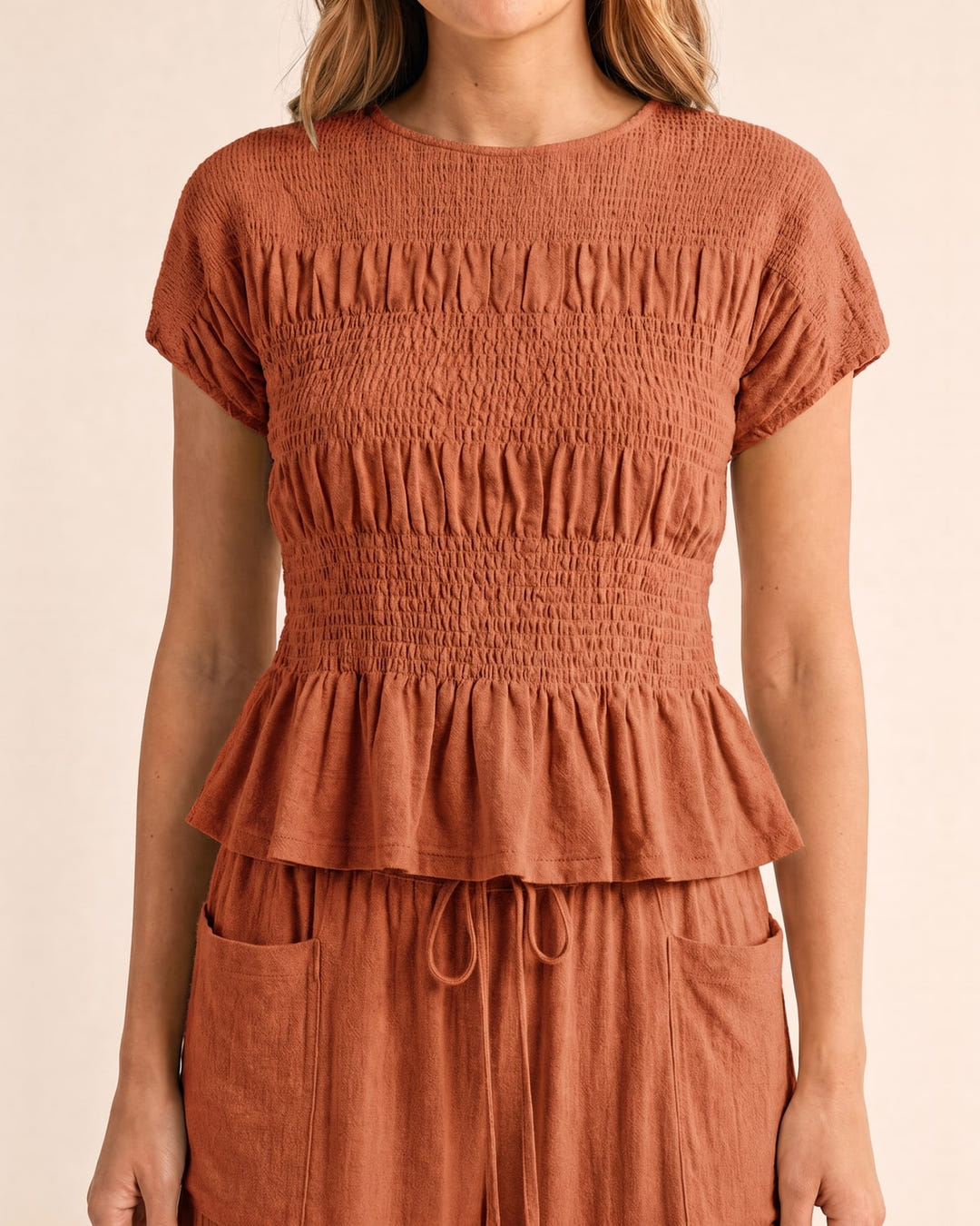Smocked top and wide-leg pants set in rust, close-up of the smocked top