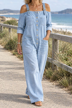 Off-shoulder denim jumpsuit in light blue on a coastal walk