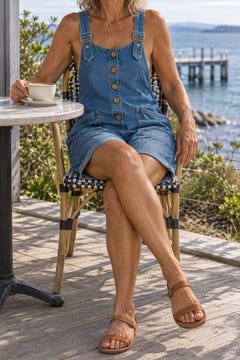 Relaxed denim overall shorts in blue at a seaside cafe