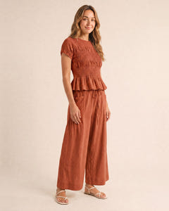 Smocked top and wide-leg pants set in rust, walking