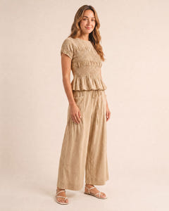 Smocked top and wide-leg pants set in sand, walking